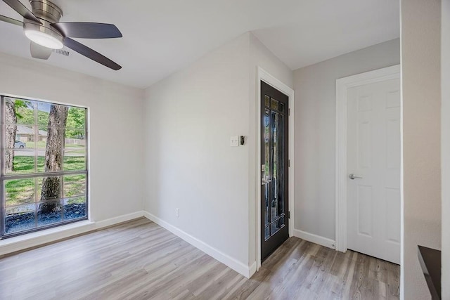 spare room featuring baseboards, light wood-type flooring, visible vents, and a ceiling fan