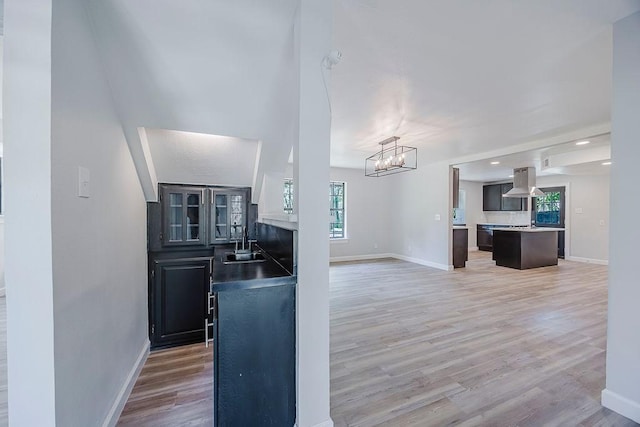 interior space with an inviting chandelier, light wood-style flooring, a sink, baseboards, and open floor plan