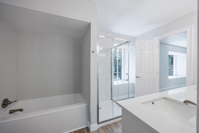 bathroom featuring wood finished floors, vanity, a bath, and a marble finish shower