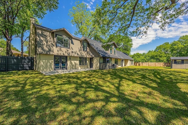 rear view of property with a chimney, brick siding, a fenced backyard, and a yard