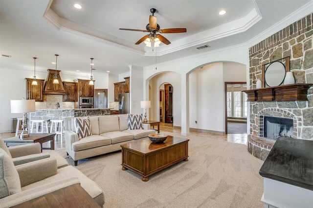 living area featuring visible vents, arched walkways, ceiling fan, and crown molding
