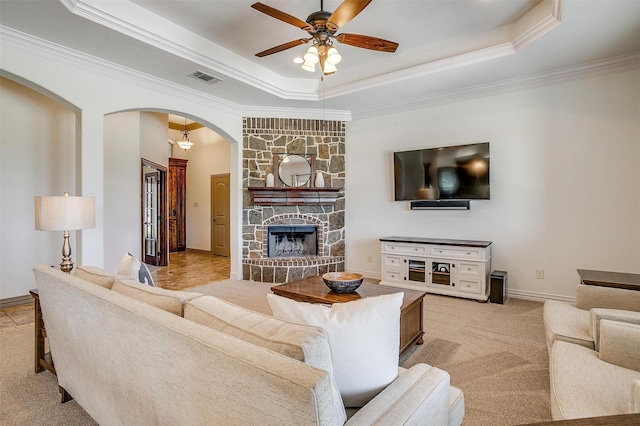 living area with light colored carpet, a raised ceiling, visible vents, arched walkways, and a ceiling fan