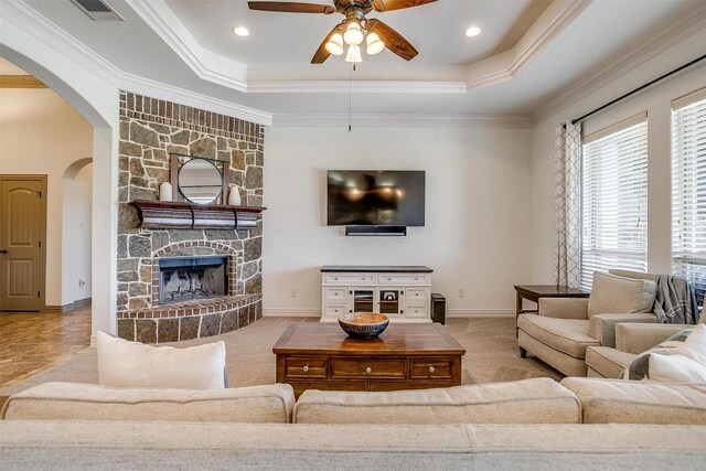 carpeted living area with visible vents, arched walkways, ceiling fan, and a tray ceiling