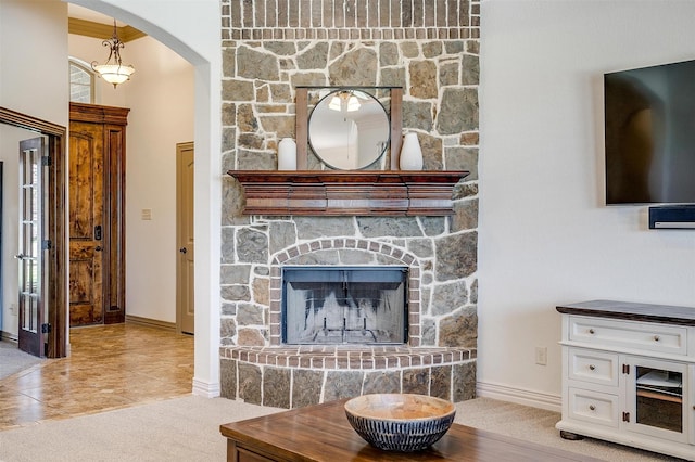 living area featuring baseboards, arched walkways, and a fireplace