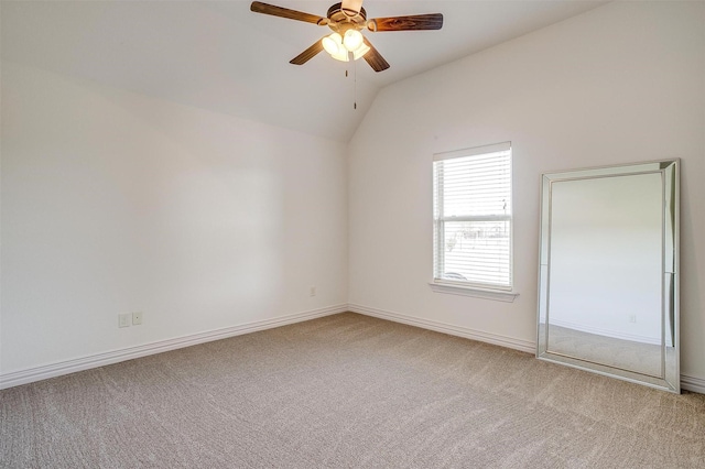 carpeted empty room featuring baseboards, a ceiling fan, and vaulted ceiling