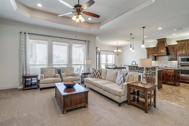 living area with recessed lighting, a tray ceiling, visible vents, ornamental molding, and ceiling fan with notable chandelier