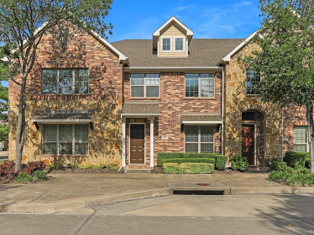multi unit property featuring brick siding, stone siding, and roof with shingles