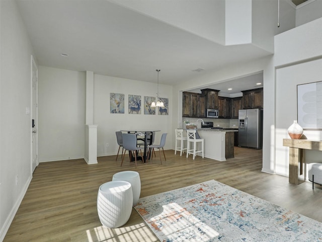 living room featuring baseboards, recessed lighting, an inviting chandelier, and light wood-style floors