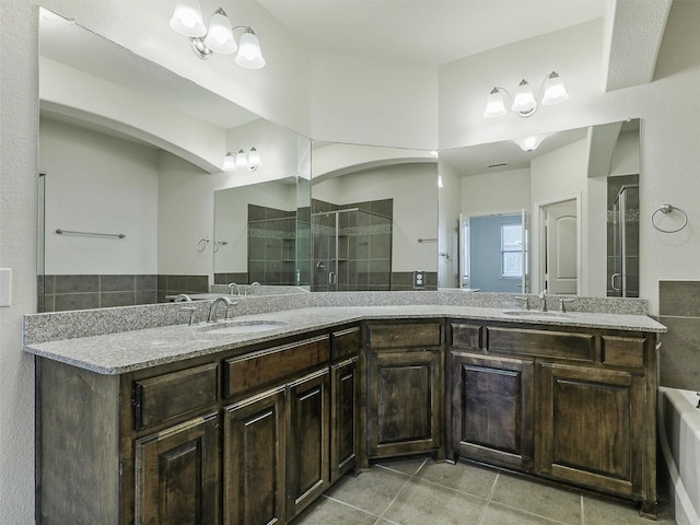 bathroom with a tile shower, tile patterned flooring, double vanity, and a sink