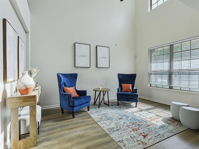 living area with a towering ceiling, wood finished floors, and baseboards