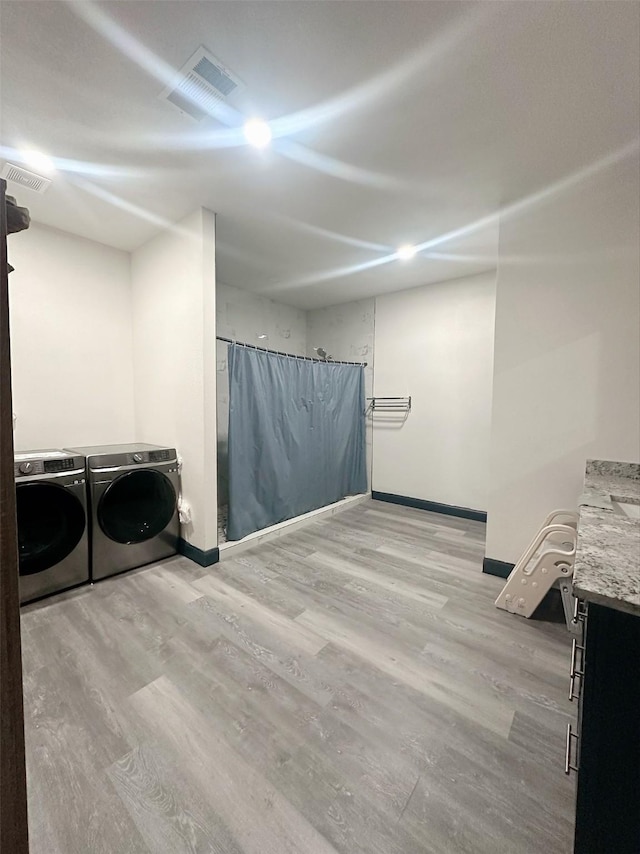 laundry area featuring washing machine and dryer, wood finished floors, laundry area, and baseboards