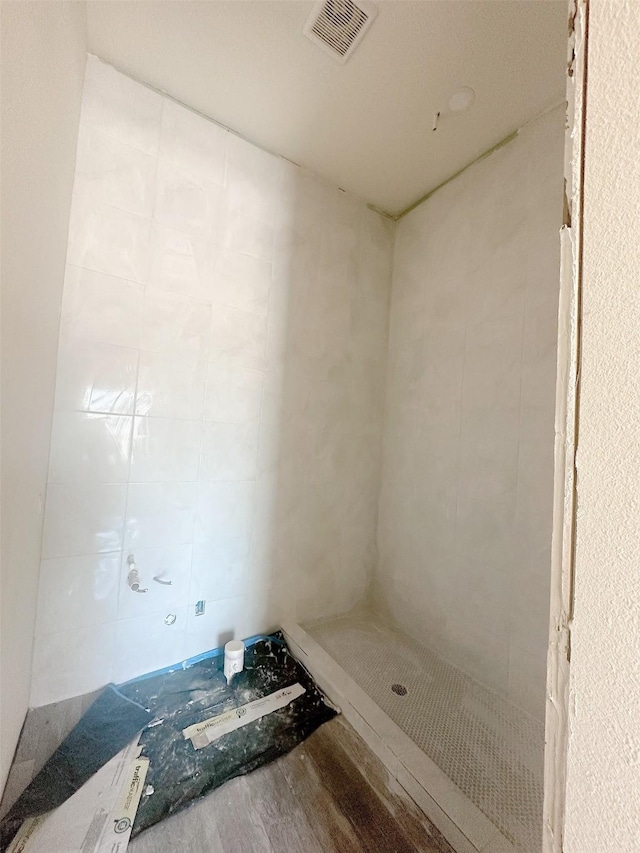 bathroom with visible vents, tiled shower, and wood finished floors