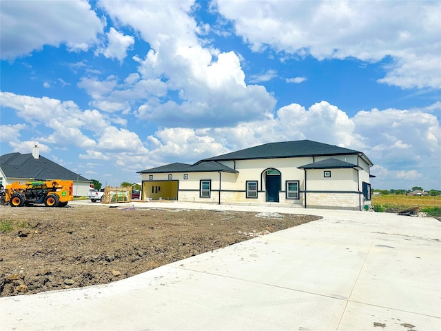 view of front of property with concrete driveway, stone siding, and stucco siding