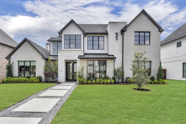 modern farmhouse style home featuring a front yard, a standing seam roof, and brick siding