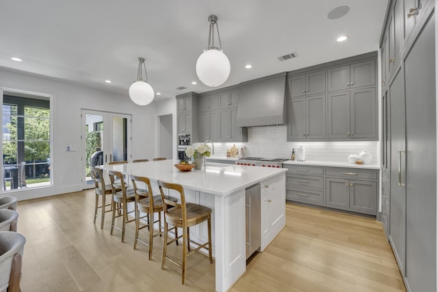 7141 Lyre Ln, Dallas, TX 75214 - kitchen featuring gray cabinets, custom range hood, backsplash, light wood-type flooring, and recessed lighting