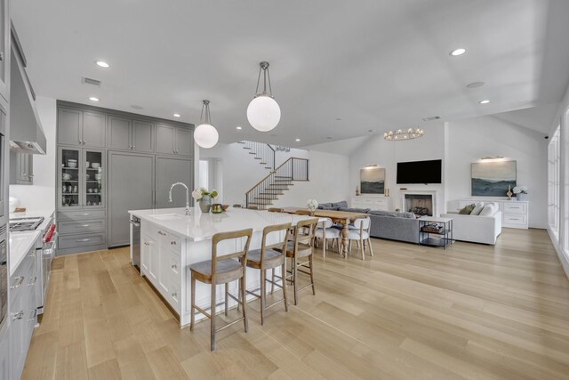 kitchen featuring a kitchen breakfast bar, light wood-style flooring, a sink, light countertops, and gray cabinets