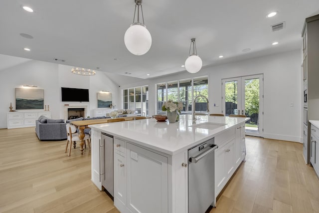 kitchen with light countertops, light wood-type flooring, dishwasher, a sink, and visible vents