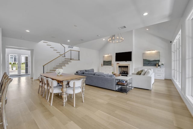 dining area with stairway, light wood-style floors, a fireplace, visible vents, and a notable chandelier