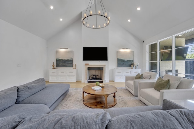 living area with recessed lighting, an inviting chandelier, a fireplace, high vaulted ceiling, and light wood-type flooring