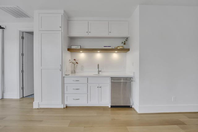 bar with stainless steel dishwasher, indoor wet bar, light wood finished floors, baseboards, and visible vents