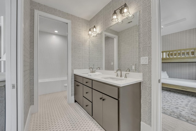 ensuite bathroom with visible vents, double vanity, ensuite bathroom, and a sink