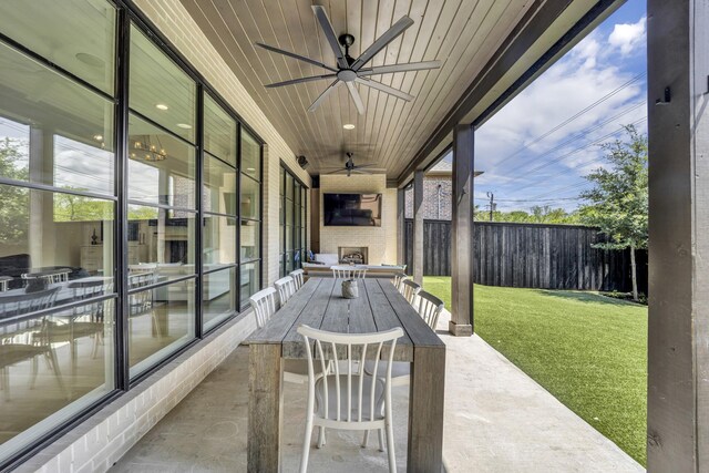 view of patio with fence, a large fireplace, and a ceiling fan