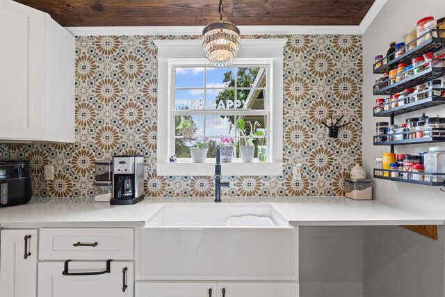 kitchen featuring an inviting chandelier, decorative backsplash, light countertops, white cabinetry, and a sink