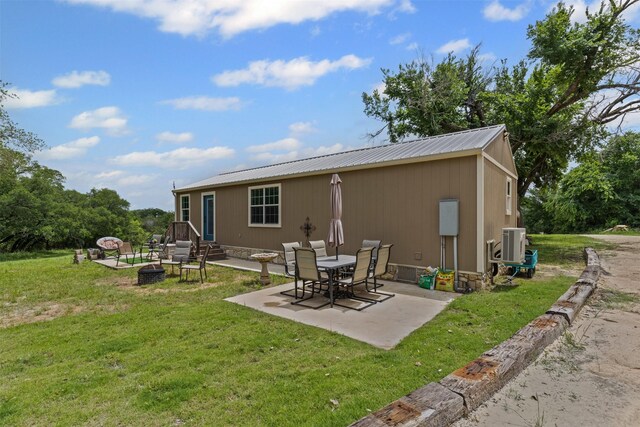 back of property featuring a yard, an outdoor fire pit, and metal roof