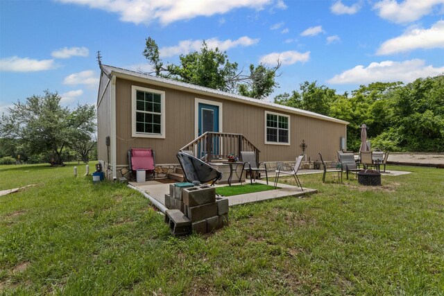 rear view of property featuring a patio, a fire pit, a yard, and metal roof