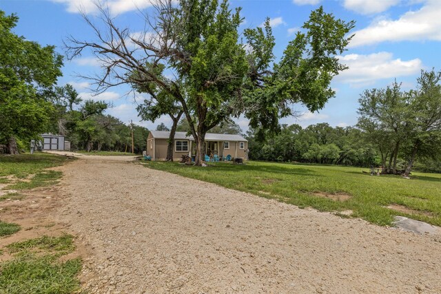 view of property's community with an outdoor structure, dirt driveway, and a yard
