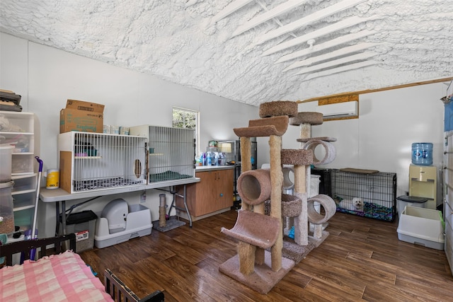 bedroom with a wall unit AC, wood finished floors, and lofted ceiling