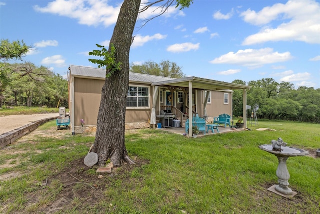 back of house featuring a lawn, a patio, and metal roof