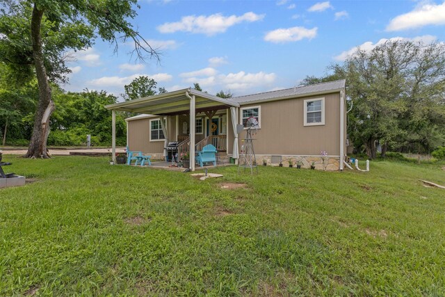 back of house with covered porch, a yard, and metal roof