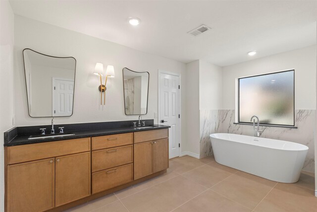 bathroom with double vanity, a sink, a soaking tub, and visible vents
