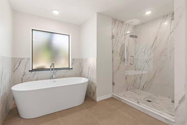 bathroom with tile patterned floors, a freestanding tub, a marble finish shower, and wainscoting