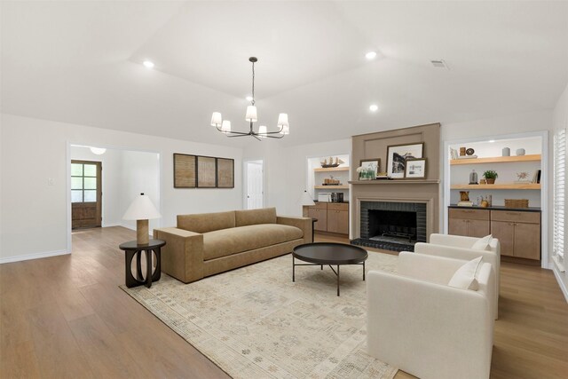 living room with an inviting chandelier, wood finished floors, a fireplace, and visible vents