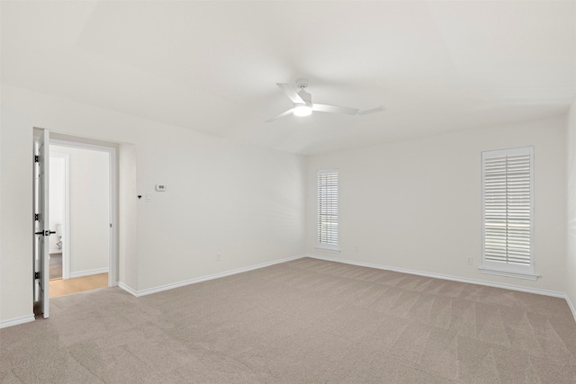spare room with baseboards, ceiling fan, and light colored carpet