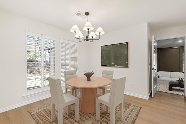 dining space with visible vents, a healthy amount of sunlight, a chandelier, and light wood-style floors