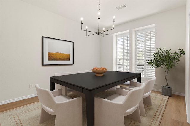 dining area with visible vents, baseboards, a chandelier, and light wood-style floors