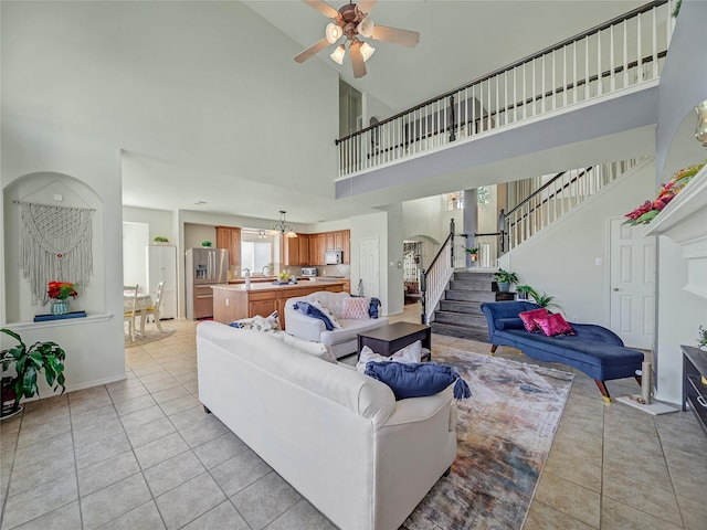 3115 Reagenea Dr, Wylie, TX 75098 - living area with stairs, ceiling fan with notable chandelier, light tile patterned floors, and high vaulted ceiling