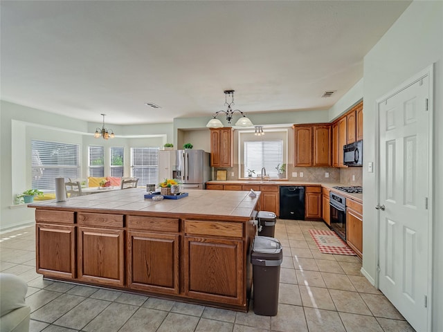 3115 Reagenea Dr, Wylie, TX 75098 - kitchen with an inviting chandelier, a center island, light tile patterned floors, backsplash, and black appliances
