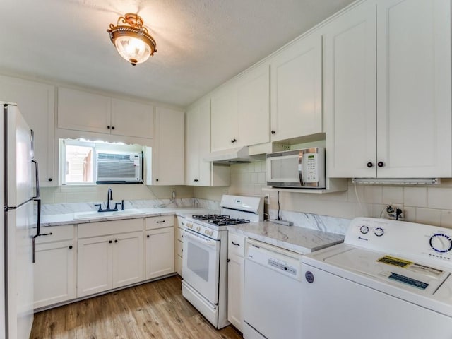 kitchen featuring washer / dryer, white appliances, light countertops, and a sink