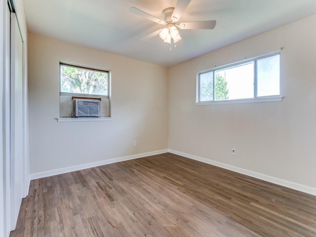 empty room featuring wood finished floors, ceiling fan, cooling unit, and baseboards