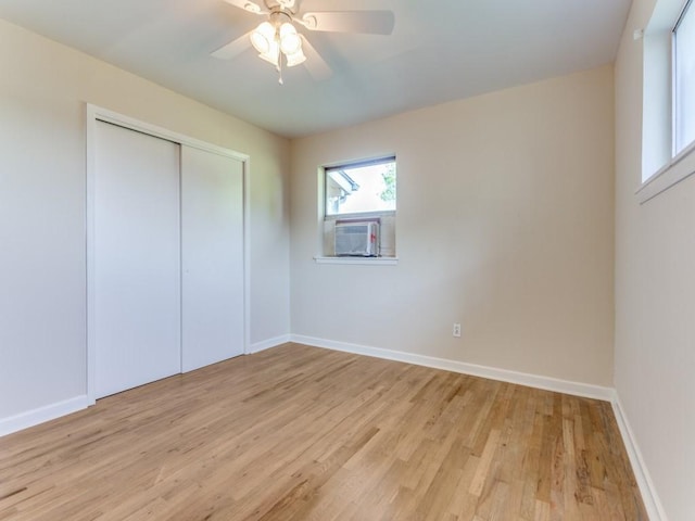 unfurnished bedroom with cooling unit, baseboards, a closet, light wood finished floors, and a ceiling fan