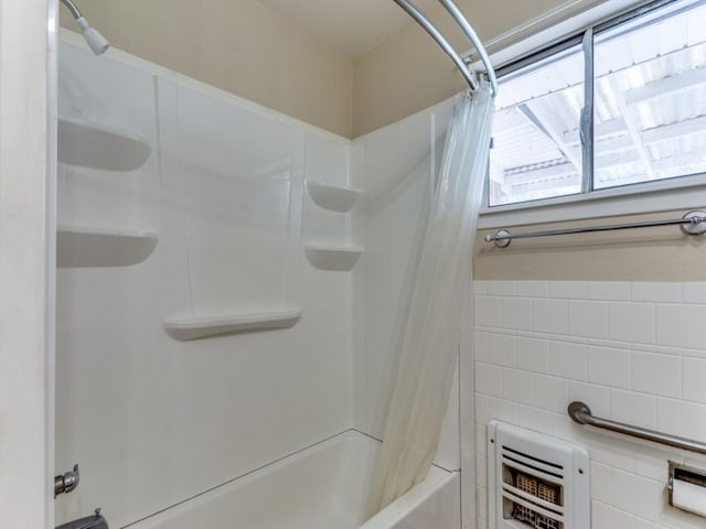 bathroom with shower / bath combo with shower curtain and heating unit