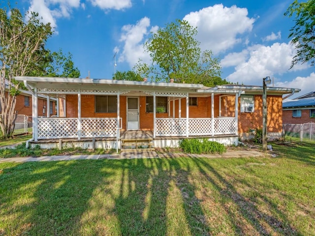 ranch-style house with fence, covered porch, a front yard, and brick siding