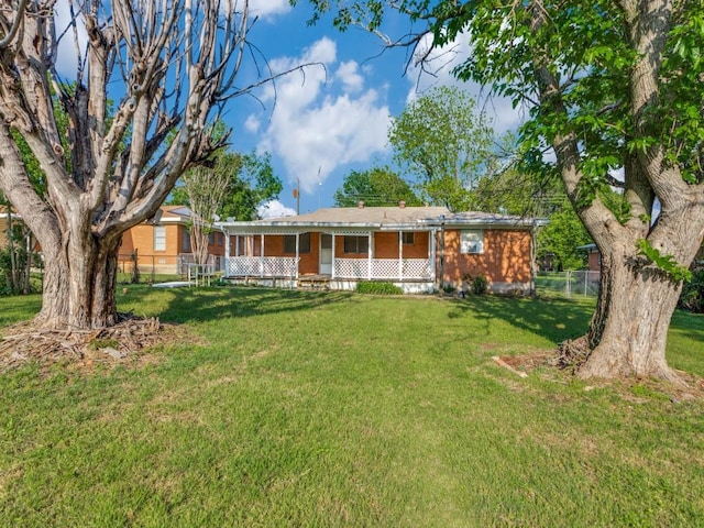 view of front of house with covered porch, fence, and a front lawn