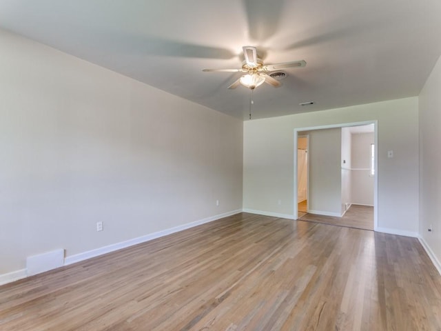 empty room with baseboards, visible vents, a ceiling fan, and light wood-style flooring