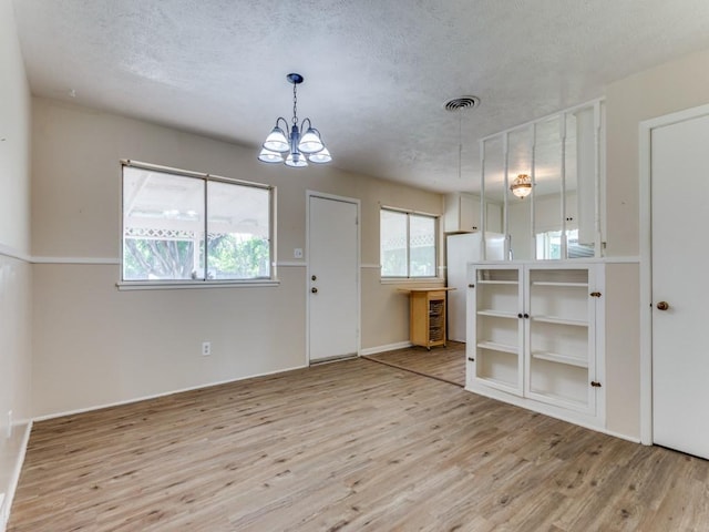 interior space featuring wood finished floors, a chandelier, white refrigerator, visible vents, and a textured ceiling
