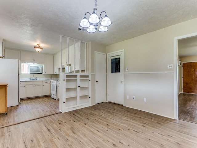 kitchen featuring white appliances, a chandelier, light countertops, a sink, and light wood-type flooring